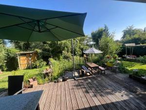 a wooden deck with a green umbrella and chairs at NurdachZeit – Ferienhaus in Schellbronn in Neuhausen