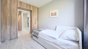 a bedroom with a white bed and a wooden cabinet at Leśne Tarasy, Sun & Snow in Dziwnówek