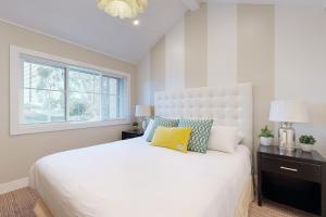 a white bedroom with a white bed and a window at On the Doorstep in Anaheim