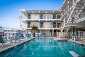 a swimming pool with chairs and a building at 301 Ocean Ave, Unit 104 - The Harbor Light in North Wildwood