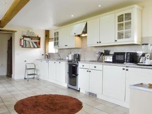a kitchen with white cabinets and a rug at White Hill Farm Cottage in Dingestow