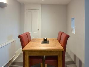 ein Konferenzraum mit einem Holztisch und roten Stühlen in der Unterkunft Coastguard Cottage in Ryde