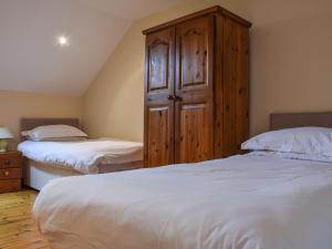 ein Schlafzimmer mit zwei Betten und einem Holzschrank in der Unterkunft Lily Cottage - Uk40101 in Dunvant + 3 Fotos