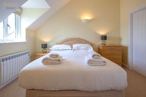 a bedroom with a white bed with towels on it at Mill Village 66, Damsel Cottage - P in Somerford Keynes +21 photos