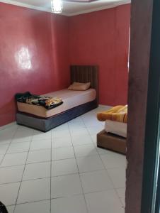 Un dormitorio con dos camas y una pared roja. en Tranquil Rental Rooms in Agadir, en Agadir 1 foto más