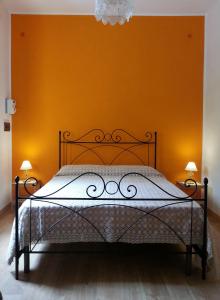 ein Schlafzimmer mit einem Bett mit einer orangefarbenen Wand in der Unterkunft Il Piccolo Baglio in Valderice