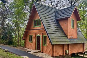 a small wooden house with a gambrel roof at Acorn Lodge in Newton Abbot