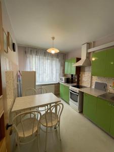 a kitchen with green cabinets and a table and chairs at Daina in Ventspils