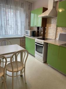 a kitchen with green cabinets and a table and chairs at Daina in Ventspils +17 photos