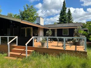 a house with a deck with a table at Cozy Family Holiday Home By Nordstrand in Nykøbing Sjælland