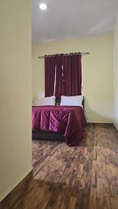 a bedroom with a bed with purple sheets and a window at Leo Home Stay - Suite Rooms Best For Family-Group-Couple-Single in Kodaikānāl