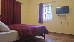 a bedroom with a bed and a tv on the wall at Leo Home Stay - Suite Rooms Best For Family-Group-Couple-Single in Kodaikānāl +63 photos