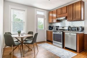 a kitchen with wooden cabinets and a table with chairs at The Upper Grove by Stay Lage in Saint Louis