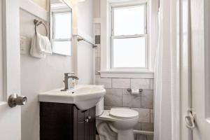 a bathroom with a sink and a toilet and a window at The Upper Grove by Stay Lage in Saint Louis +15 photos