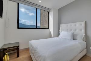 a white bedroom with a large bed and a window at Class 48 apto. 1303 - Luminoso / Vistas / Balcón in Sabaneta