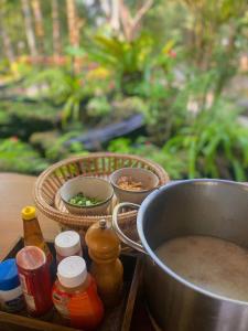a table with a pot of soup and baskets of food at บ้านสวนภูรจิตร Baansuanphurajit in Ban Nong Pa Kha