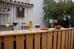 a wooden table with wine glasses and wine bottles at Hôtel La Pergola - centre ville in Capbreton