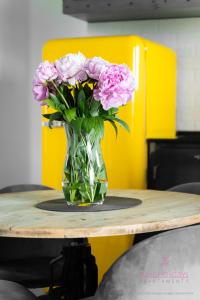 Un jarrón de flores rosas sobre una mesa. en Your Holidays Aquamarina Onyx 84, en Międzyzdroje