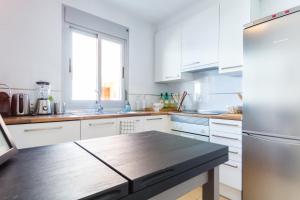 cocina con armarios blancos y mesa de madera en Casa Molinar, en Palma de Mallorca