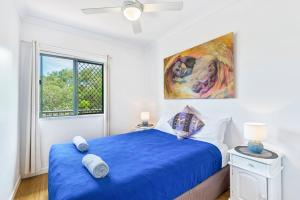 a bedroom with a blue bed and a window at Tigerlily's in Byron Bay
