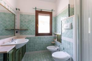 un bagno piastrellato verde con lavandino e servizi igienici di Casa Fenicottero - Pet Friendly - Funtana Meiga a Funtana Meiga Altre 11 foto