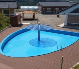 a blue pool with an umbrella and a picnic table at Hanok Stay Daldojimaeul Pension in Jangseong