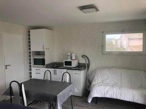 a small kitchen with a table and a bed in a room at Pérols Centre, Studio unique au dessus de notre maison avec grande terrasse in Pérols