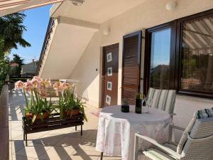eine Terrasse mit einem Tisch und Blumen auf dem Balkon in der Unterkunft Apartment Malinska, Primorje-Gorski Kotar 1 in Malinska
