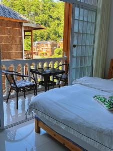 a bedroom with a bed and a balcony with a table and chairs at Tongfu Inn(In the National Park) in Zhangjiajie