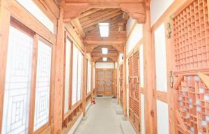 a hallway in a house with wooden walls and windows at Ulsan Eoryeondang Hanok Stay in Ulsan