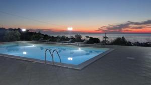 a swimming pool with a sunset in the background at La Valle degli Ulivi in Acquedolci