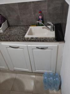 a kitchen counter with a sink and some water bottles at Appartement 2 à Carthage byrsa in Douar ech Chott +13 photos