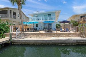 Una casa con sillas y sombrillas al lado de un cuerpo de agua. en Coastal Breeze Siesta – Entire 4-Unit Complex with Dock, en Sarasota