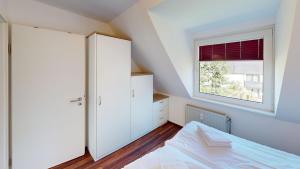 a white bedroom with a bed and a window at Gorch Fock - 11 in Cuxhaven