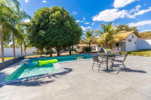 a pool with a table and chairs next to a house at Refúgio 4 Suítes c/ Piscina, Sinuca e Área Gourmet in Caldas Novas