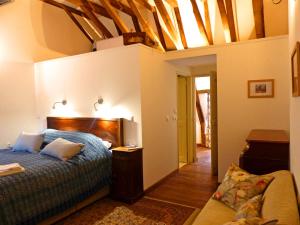 a bedroom with a bed and a couch in it at Élégant cottage médiéval restauré avec piscine, cheminée, proche du golf et attractions culturelles - FR-1-489-335 in Hérisson +28 photos