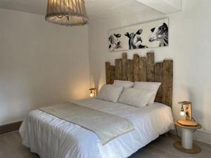 a bedroom with a white bed with a wooden headboard at Charmant Gîte de Campagne avec Confort et Détente - FR-1-489-348 in Besson +6 photos