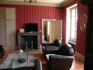 a living room with red walls and leather chairs and a fireplace at Maison rénovée 19è, piscine chauffée, sauna, spa, grand parc, proche de la nature spacieuse et tout confort. - FR-1-489-399 in Cérilly