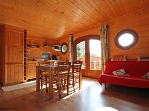 Una sala de estar con un sofá rojo y una mesa. en Chalet bois avec terrasse, animaux acceptés, nature près Alençon - FR-1-497-184, en Le Plessis