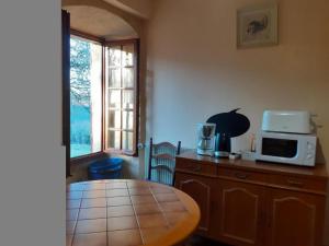 a kitchen with a table and a microwave on a counter at Maison avec piscine chauffée privée, proche Lascaux et Dordogne, idéale famille et détente - FR-1-616-123 in Auriac-du-Périgord