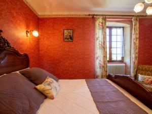 a bedroom with a bed with red walls and a window at Maison avec piscine chauffée privée, proche Lascaux et Dordogne, idéale famille et détente - FR-1-616-123 in Auriac-du-Périgord