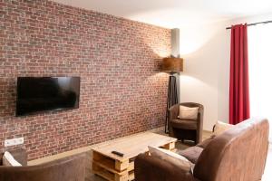 a living room with a brick wall with a tv at Gîte Jean Scafer, Piscine chauffée, Wifi, Salle de jeux, Animaux de la ferme in Beynat