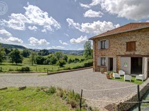 an external view of a house with a gravel driveway at Gîtes Champêtres Rénovés avec Terrasse, Jardin, et Activités pour Familles et Amis - FR-1-496-304 in Belmont-de-la-Loire
