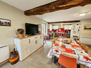 Un comedor con una mesa con sillas y un televisor. en Charmant gîte en pierre près de Chinon, jardin privatif - FR-1-381-608, en Sazilly