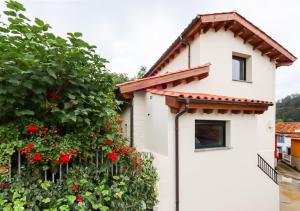 a white house with red flowers on the side of it at MC Vega- Mi Casina con vistas al mar in Ribadesella