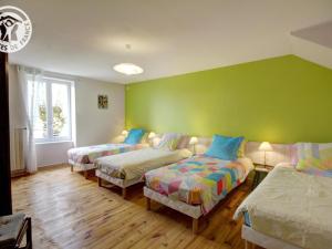 Habitación con 3 camas y pared verde. en Gîte rural familial avec jardin, terrasse et équipements modernes près du Parc Livradois Forez - FR-1-496-22, en Chérier