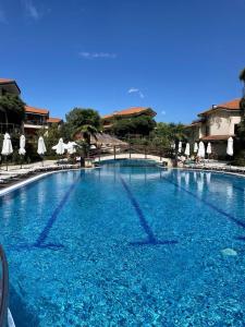 a large blue swimming pool with chairs and umbrellas at Family Paradise in Laguna Beach Hotel in Sozopol