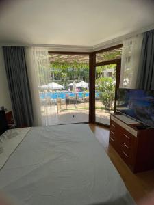 a bedroom with a bed and a view of a pool at Family Paradise in Laguna Beach Hotel in Sozopol