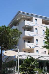 ein weißes Gebäude mit Bäumen davor in der Unterkunft Hotel Caribia Pinarella in Cervia
