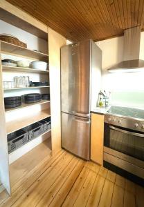 a kitchen with a stainless steel refrigerator and wooden floors at Architectural Cottage On 7000 Sqm Nature Plot in Hadsund